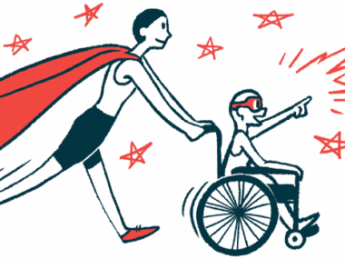 An adult with a red cape pushes a child in a wheelchair who's seen wearing a superhero eye mask.