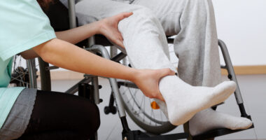 Physical therapist doing leg exercises with person in wheelchair