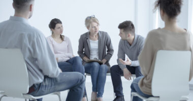 People sitting in chairs in a circle having a group meeting