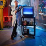 Bill Nye the Science Guy is pictured leaning against a video monitor in his lab.