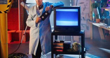 Bill Nye the Science Guy is pictured leaning against a video monitor in his lab.