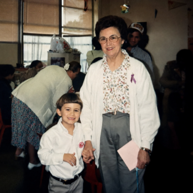 An old photograph shows a young boy holding hands with his grandmother.
